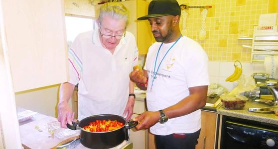 A volunteer from a bereavement charity offering support to a widower to cook a meal for himself.