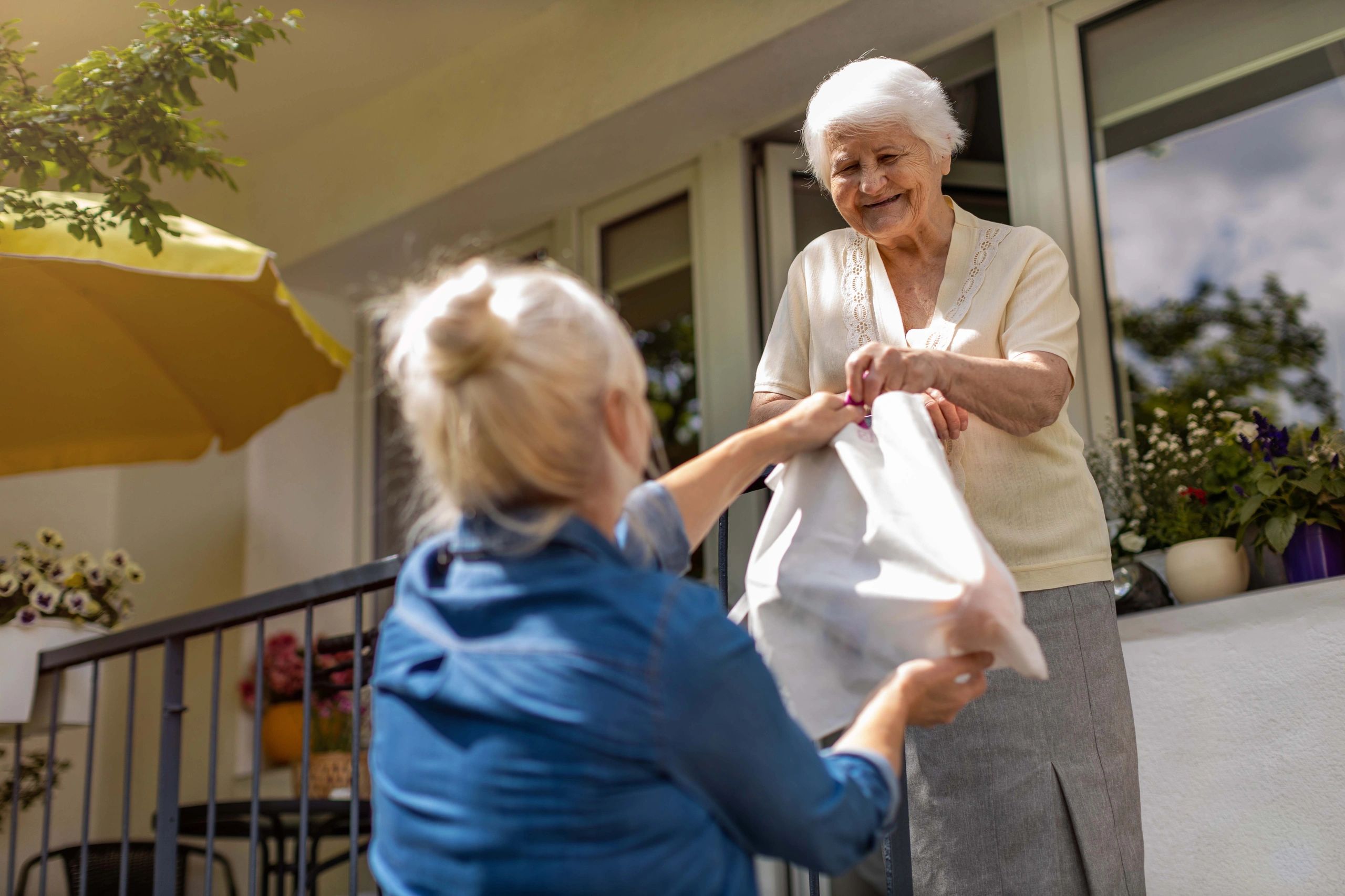 Volunteer delivering a meal to an elderly woman on her porch