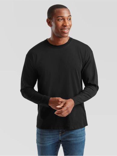 Smiling man wearing a black long-sleeve shirt and blue jeans against a gray background.