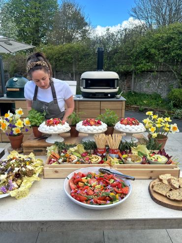 Woman preparing fresh, colorful outdoor food display.