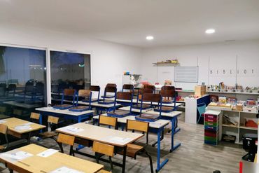 Empty classroom with chairs on desks and educational materials around.
