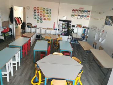 Bright and colorful kindergarten classroom with small tables and chairs.