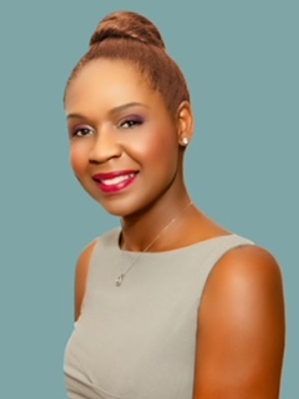 Smiling woman with an elegant bun hairstyle and light gray sleeveless top.