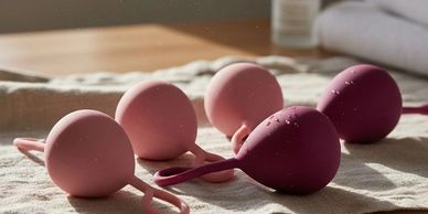 Set of silicone Kegel balls in pink and purple on a cloth.
