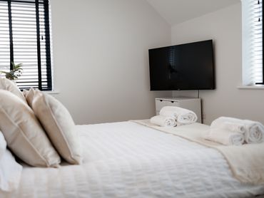 modern bedroom airbnb smart tv black wooden blinds double king queen bed feature cushions