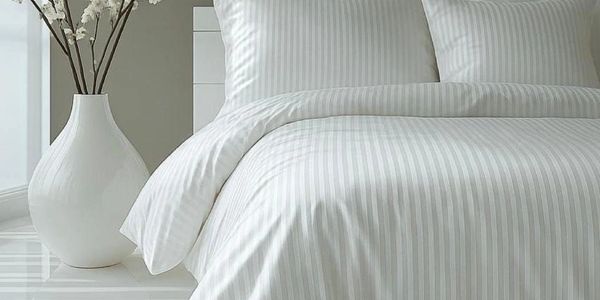 Elegant white striped bedding set with matching pillows and vase.