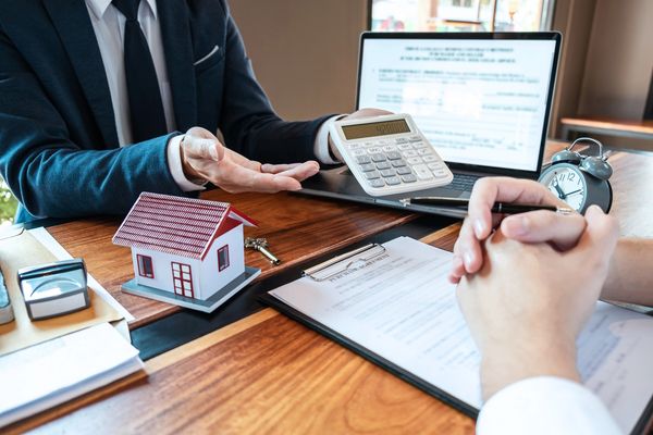 A loan officer discusses mortgage details with a client, showing calculations on a calculator