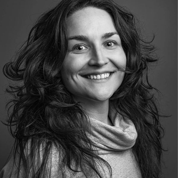 Black and white portrait of a smiling woman with wavy hair.