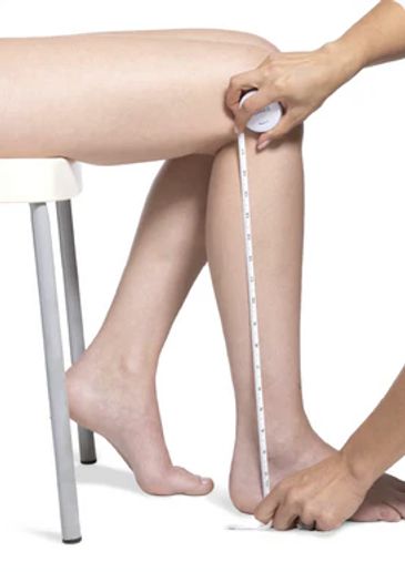Person measuring their lower leg with a tape measure.