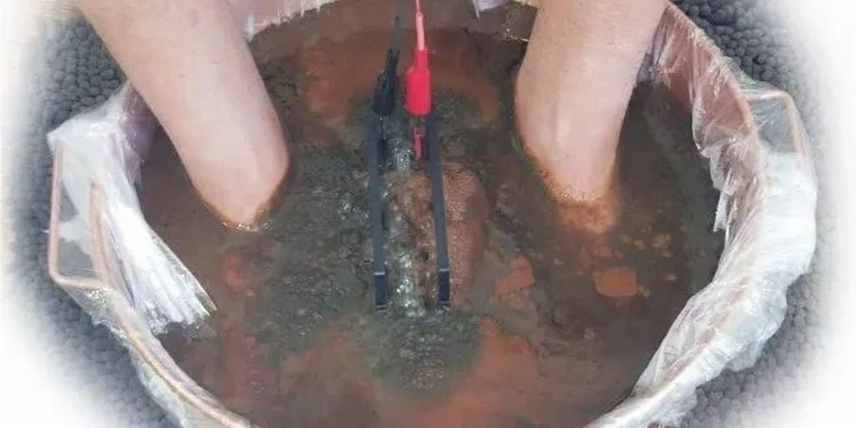 Feet submerged in muddy water with electrodes.
