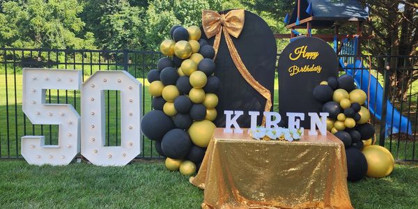 Golden and black 50th birthday party setup outdoors.