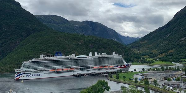 P&O Cruises ship docked in a scenic fjord.