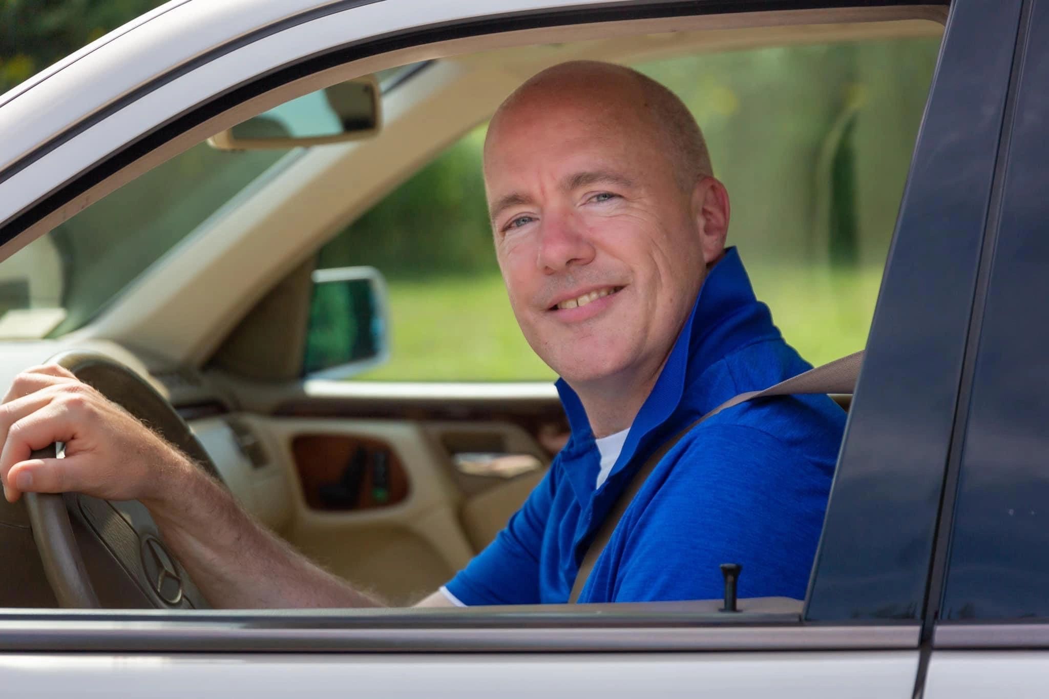 Smiling man driving a car.