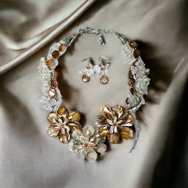 Elegant floral necklace and matching earrings with pearl and shell details.