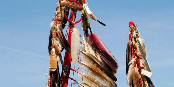 Decorative Native American feathered staffs against a clear blue sky.