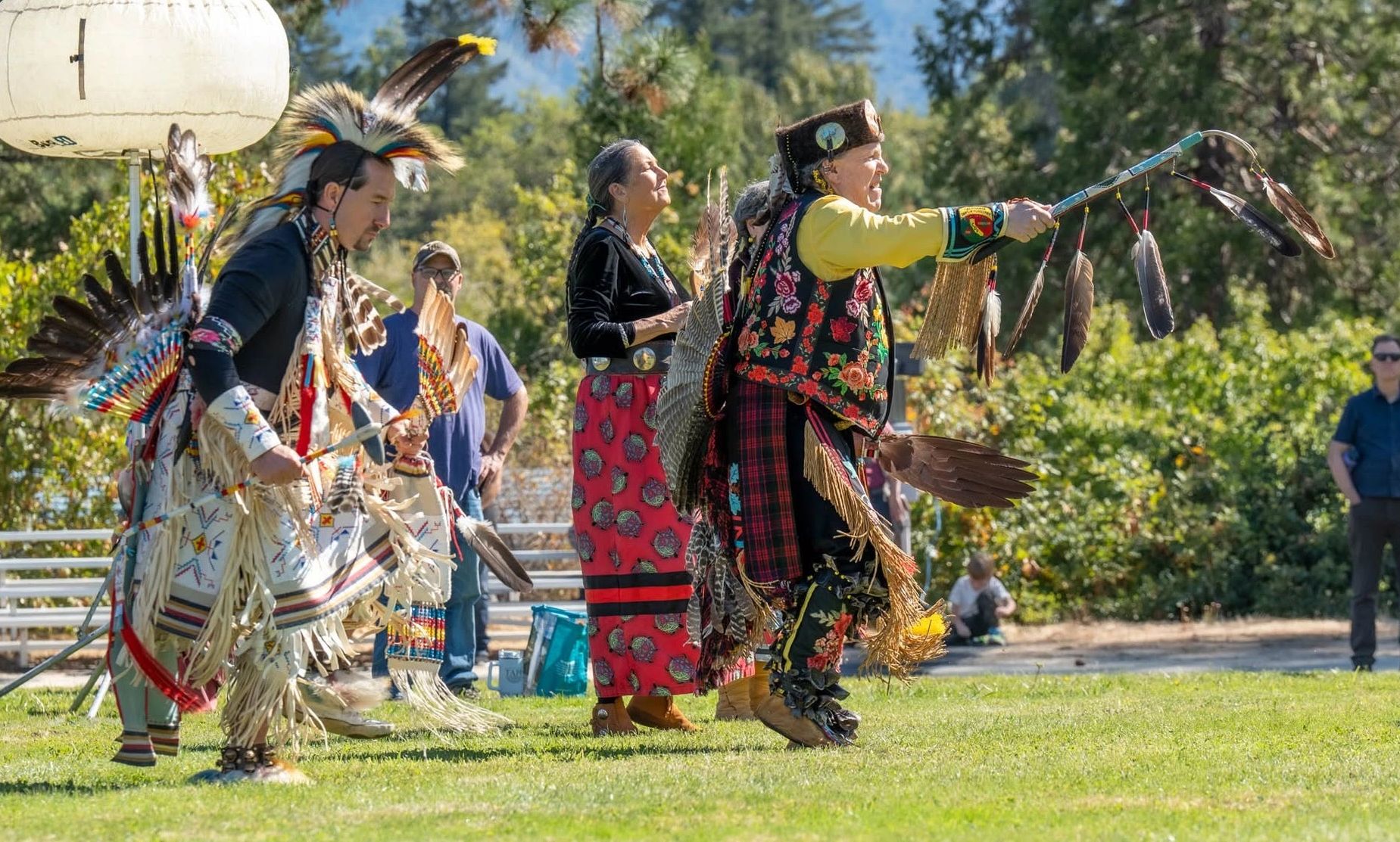 Native American dancers performing in traditional attire outdoors.