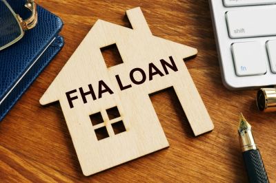 Wooden house cutout with FHA Loan text on a desk.