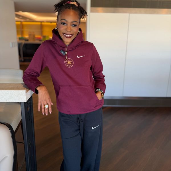 Woman smiling in maroon hoodie and black pants.