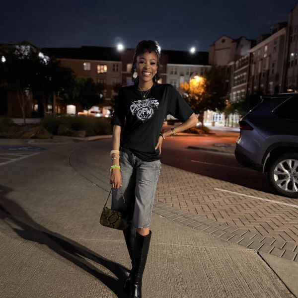 Young woman smiling on street at night wearing black boots.