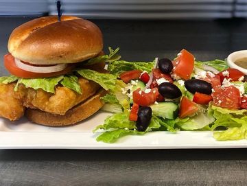 Fish burger with a greek salad