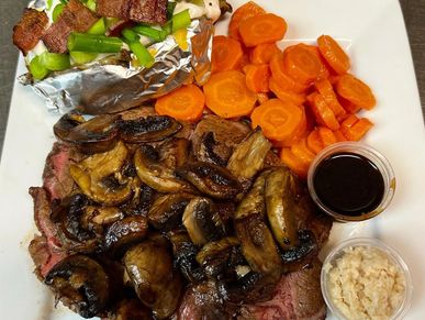 Prime rib with mushrooms, loaded baked potato, and carrots