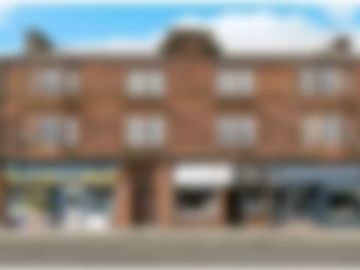 Blurred image of a brick building with shops at street level.