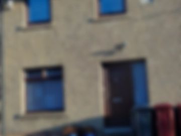 Blurred image of a building facade with windows and a door.