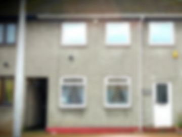 Blurry image of a residential building facade with windows and a door.