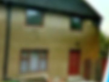 A blurry image of a house with a red door and windows.