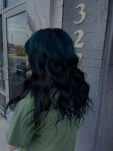 Person with long, wavy dark hair with teal highlights.