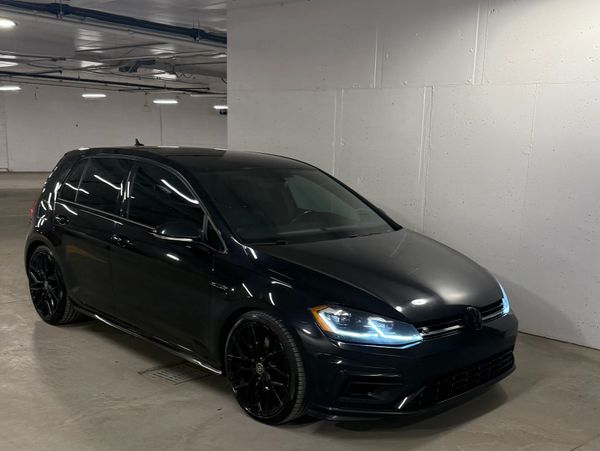 Sleek black Volkswagen hatchback parked in a dimly lit garage.