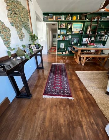 Cozy living space with wooden floors, green bookshelf, and rustic furniture.