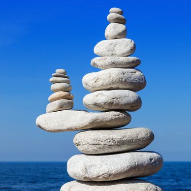 Balanced stacks of smooth white stones against a clear blue sky.