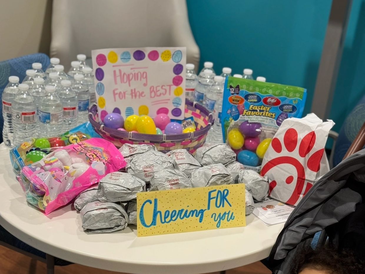 Table with bottled water, snacks, Easter eggs, and encouraging signs.