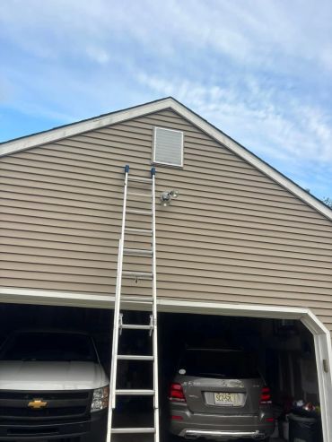 Ladder leaning against a garage with two vehicles parked inside.