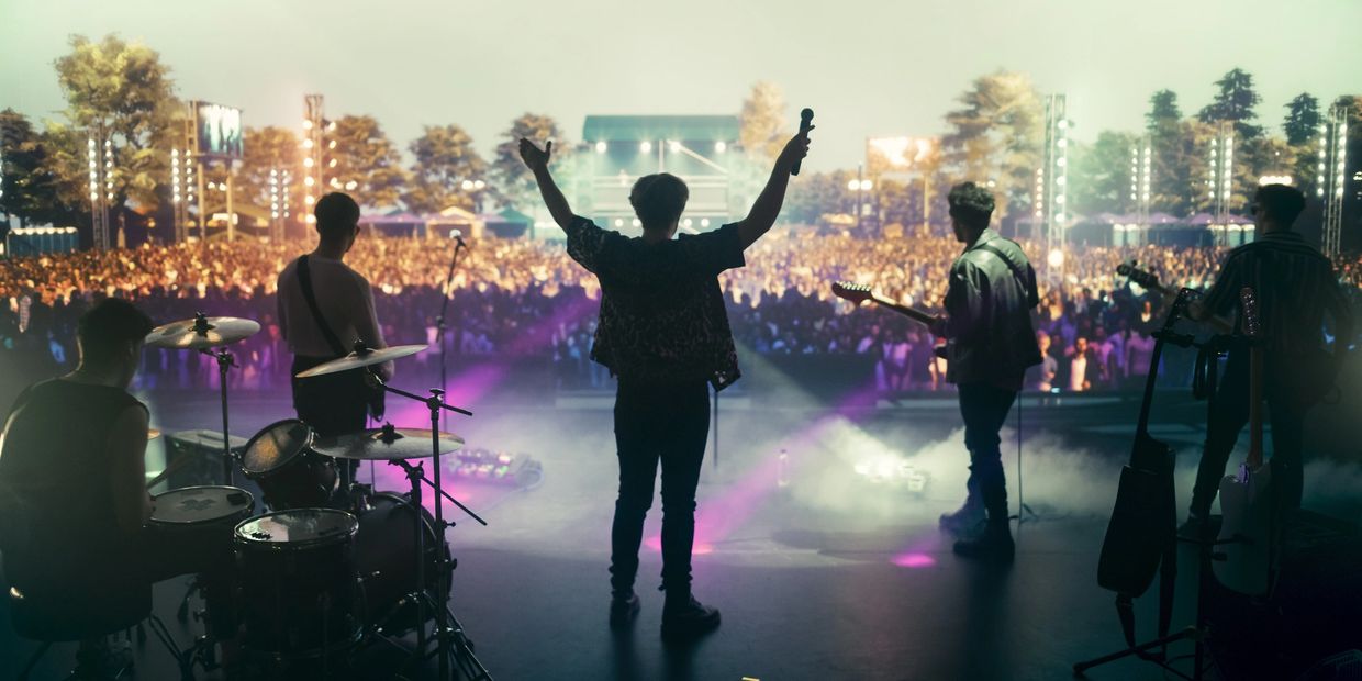 Band performing on stage in front of a large crowd at an outdoor concert.