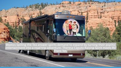 A large RV travels through a desert canyon landscape under clear blue sky.