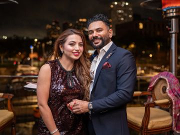 A well-dressed couple posing together at a nighttime outdoor event.