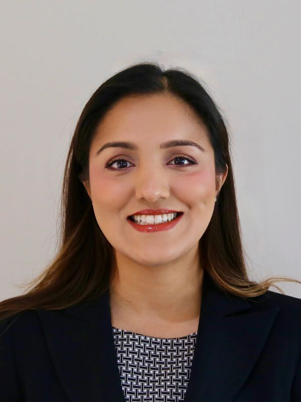 Professional woman smiling confidently in business attire against a plain background.