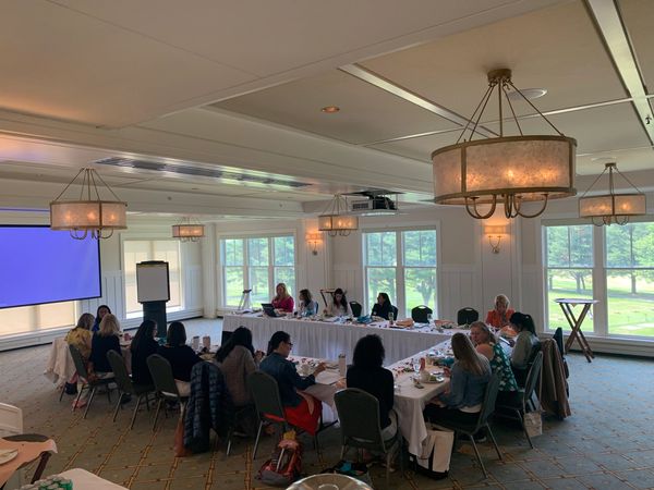 A group of women sitting at a large table as a conference is being held