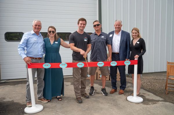 A group of people smiling for a ribbon cutting ceremony
