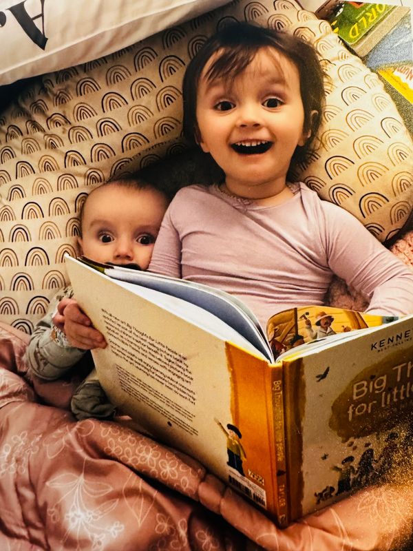 Two children reading a book together in bed.