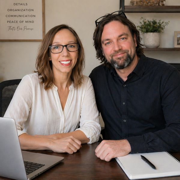 Smiling colleagues at a desk with laptop and notebook.