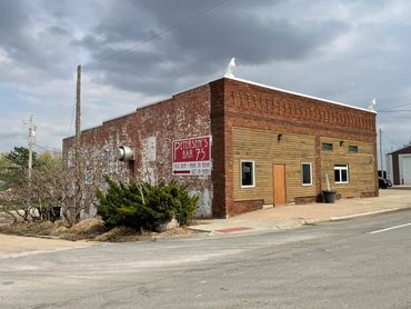 Old brick building with Petersen's Bar 75 sign under cloudy sky.