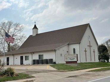 White church building with crosses and an American flag outside.