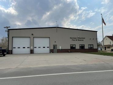 Herman Volunteer Fire & Rescue station with large garage doors and American flag.