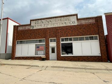 Old brick storefront with faded signage and boarded windows.