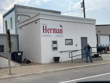 A man in overalls walks near the Village of Herman building in Nebraska.