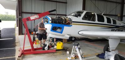Mechanic working on airplane engine in a hangar.