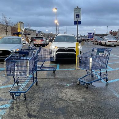 An image of three stranded shopping carts blocking the accessible parking space at a store.